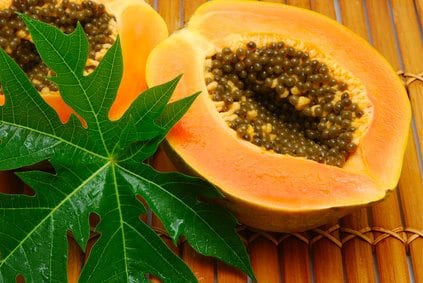 cut papaya and wet leaf on bamboo